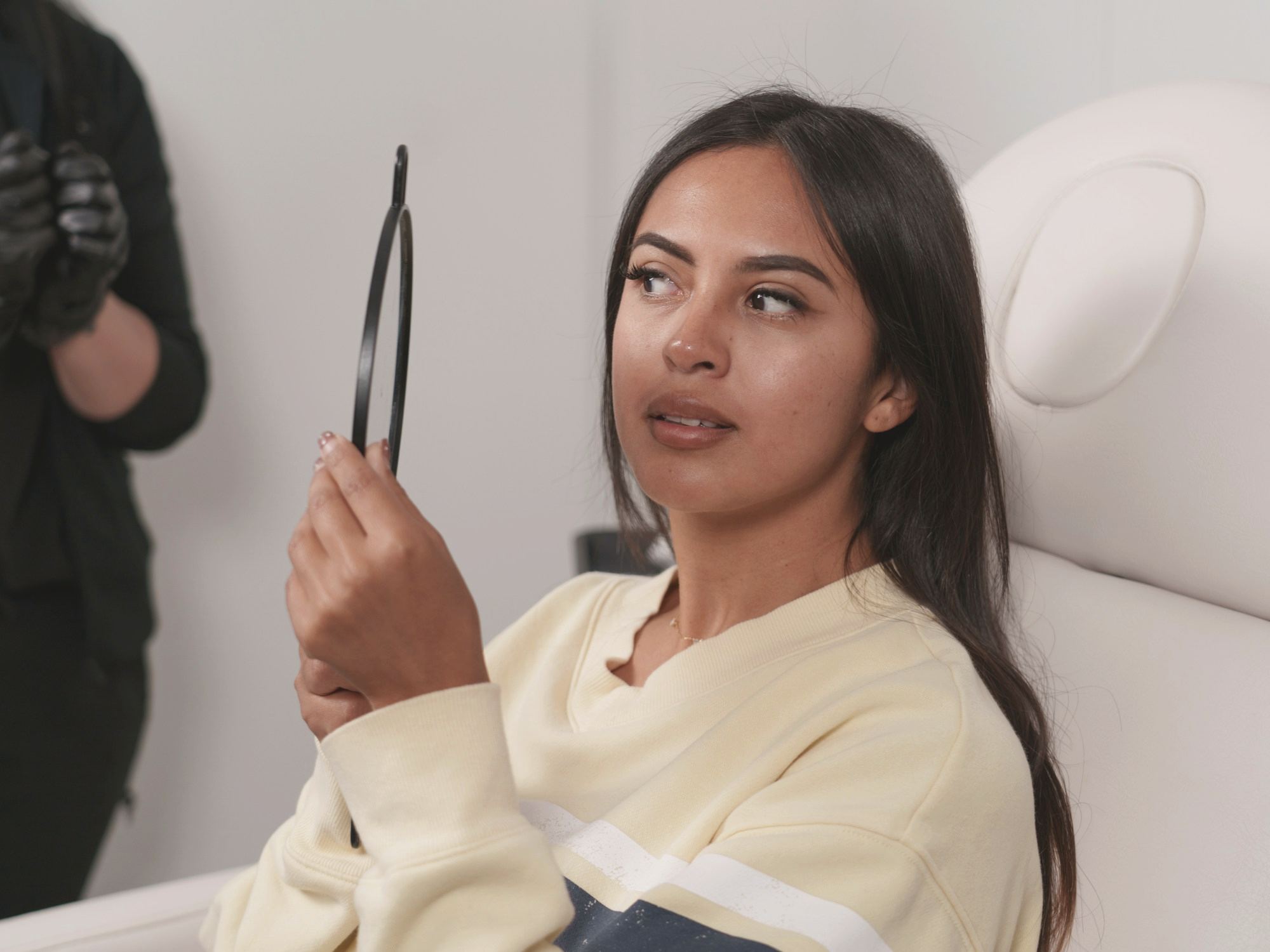 A woman looking into a hand mirror