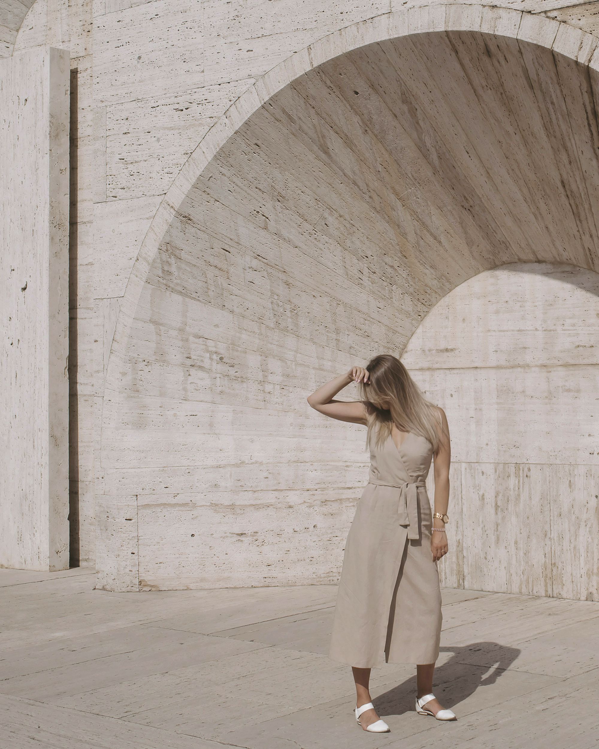 A woman standing in a pale stone archway